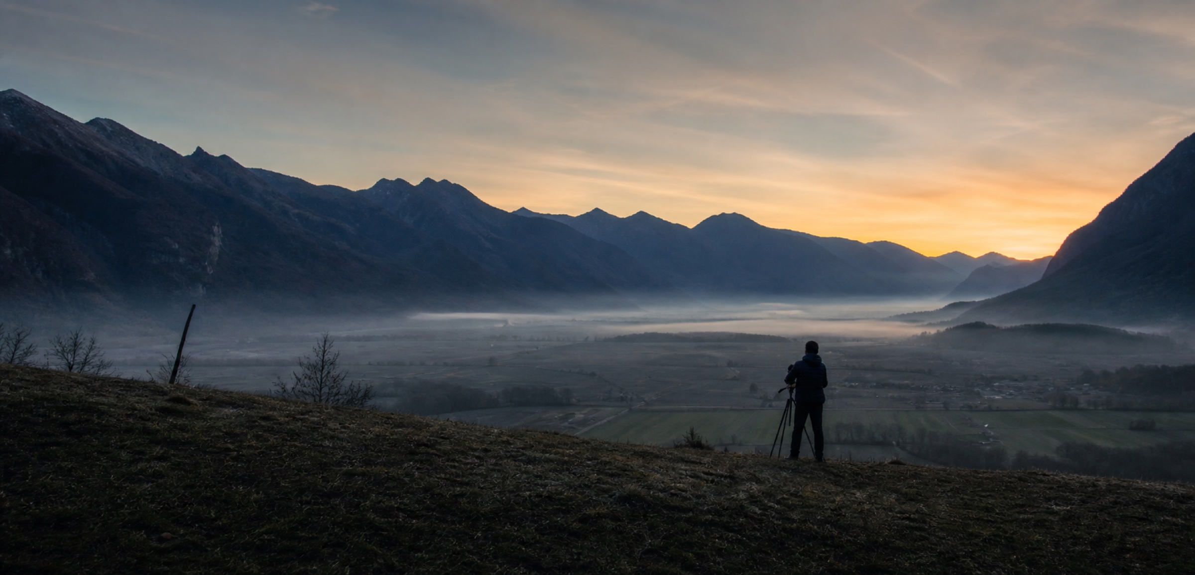 Un photographe contemple la vallée alpine à l’aube